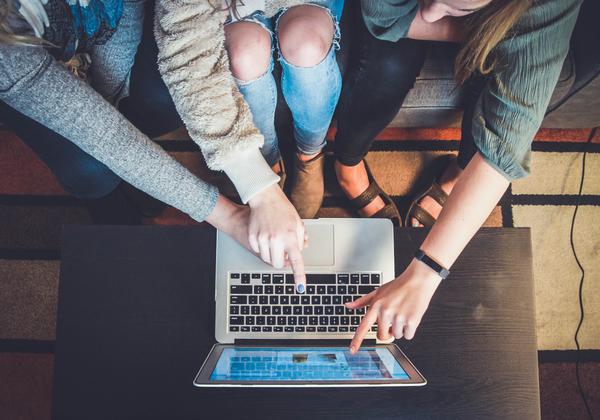 Three people pointing at a laptop