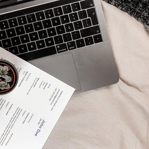 A CV on top of a laptop upon a bed