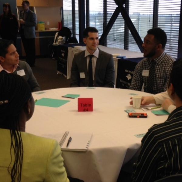 A group of students and employers talking at a table during the LMRT