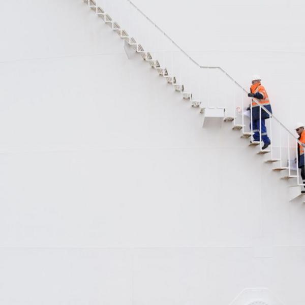 A photo of 3 men in work clothes climbing a staircase