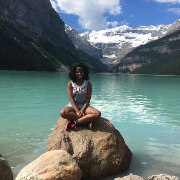 Taffii Ndlovu Hospitality Management student sitting on a rock by a lake
