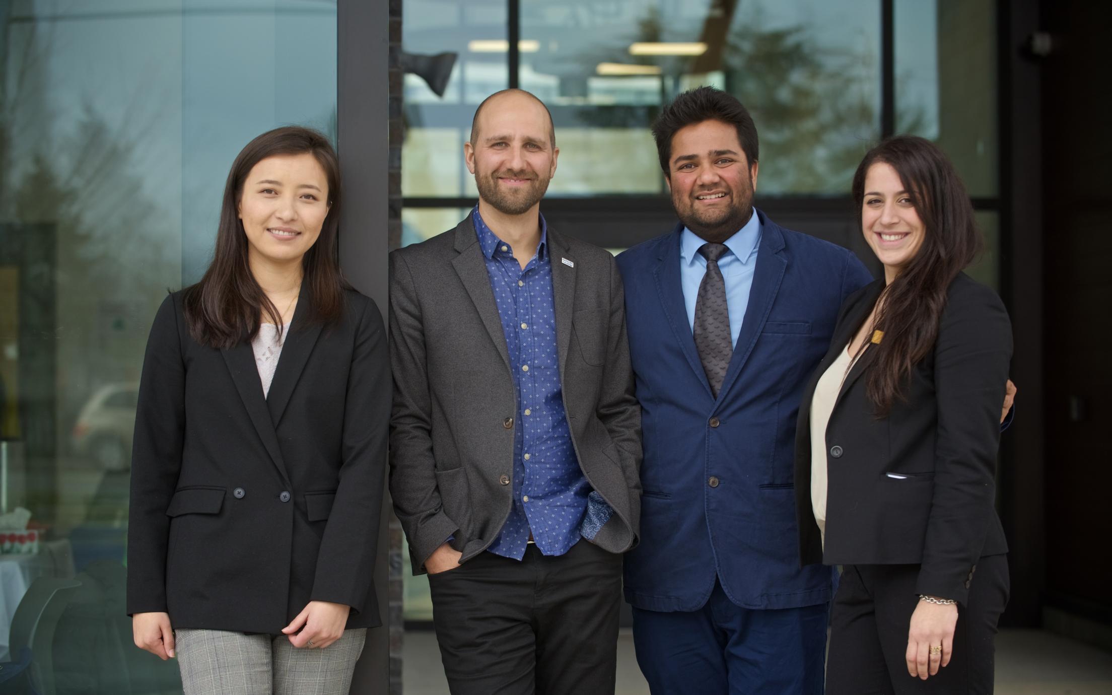 Four MBA students in business attire standing together for a photo