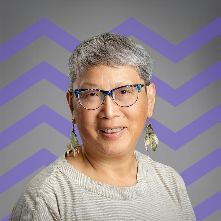 Smiling woman wearing glasses and a white shirt with a purple mountain pattern behind her