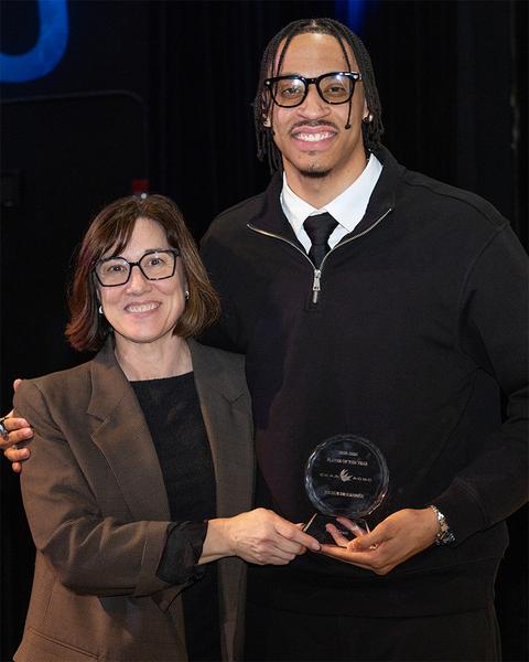 A tall man accepts a CCAA award from a woman. 