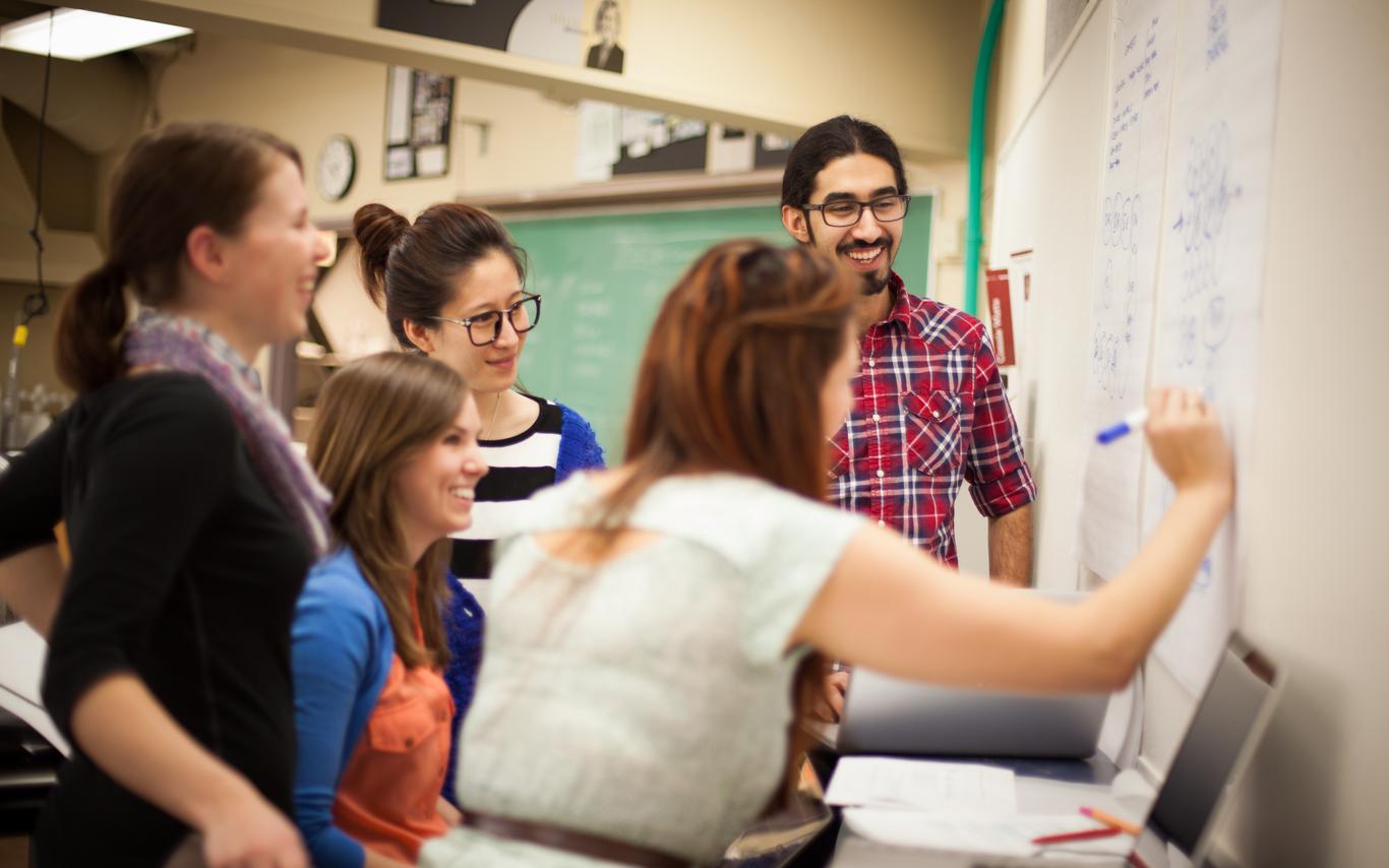 Three students and their PSL Leader in a class room working on problems