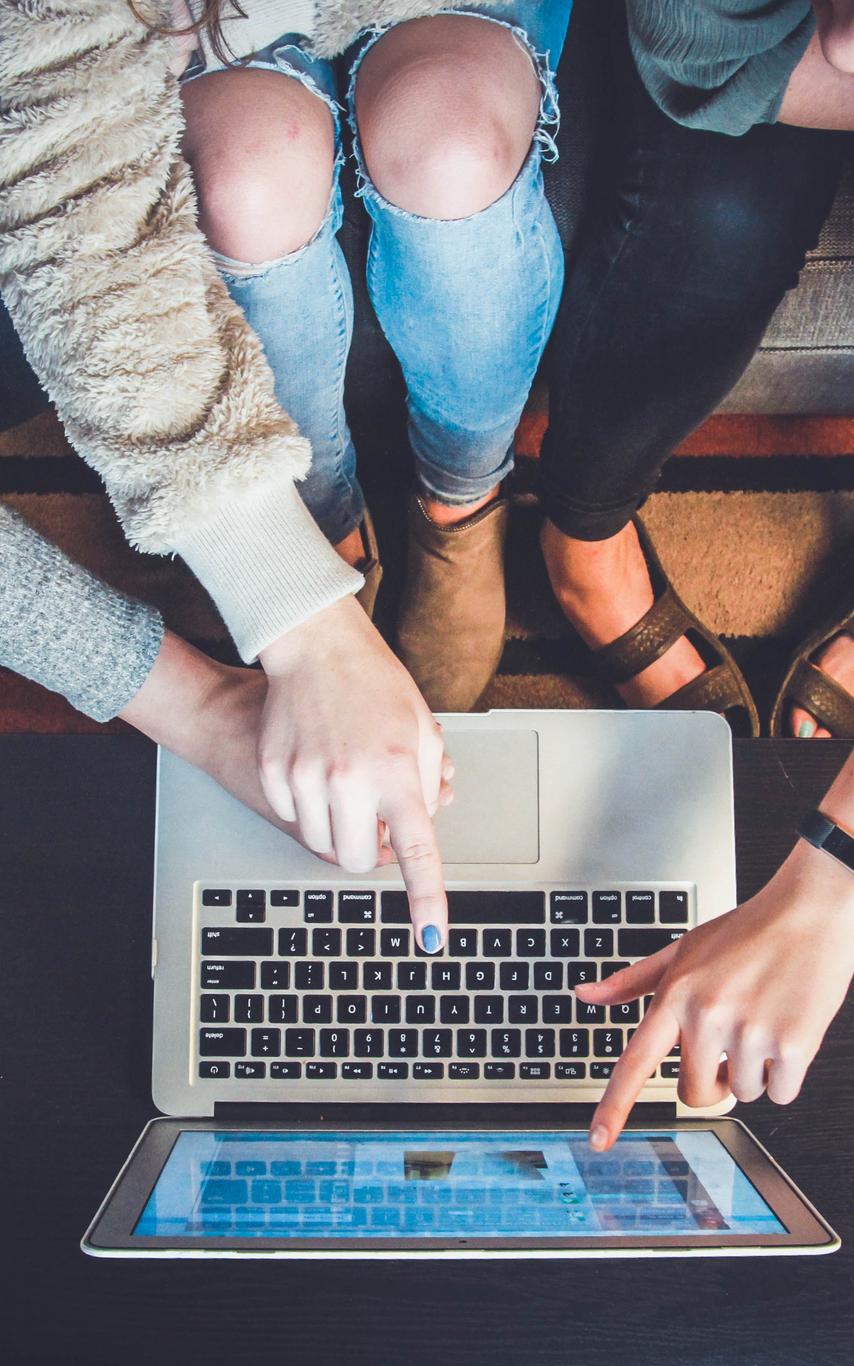 Three people pointing at a laptop